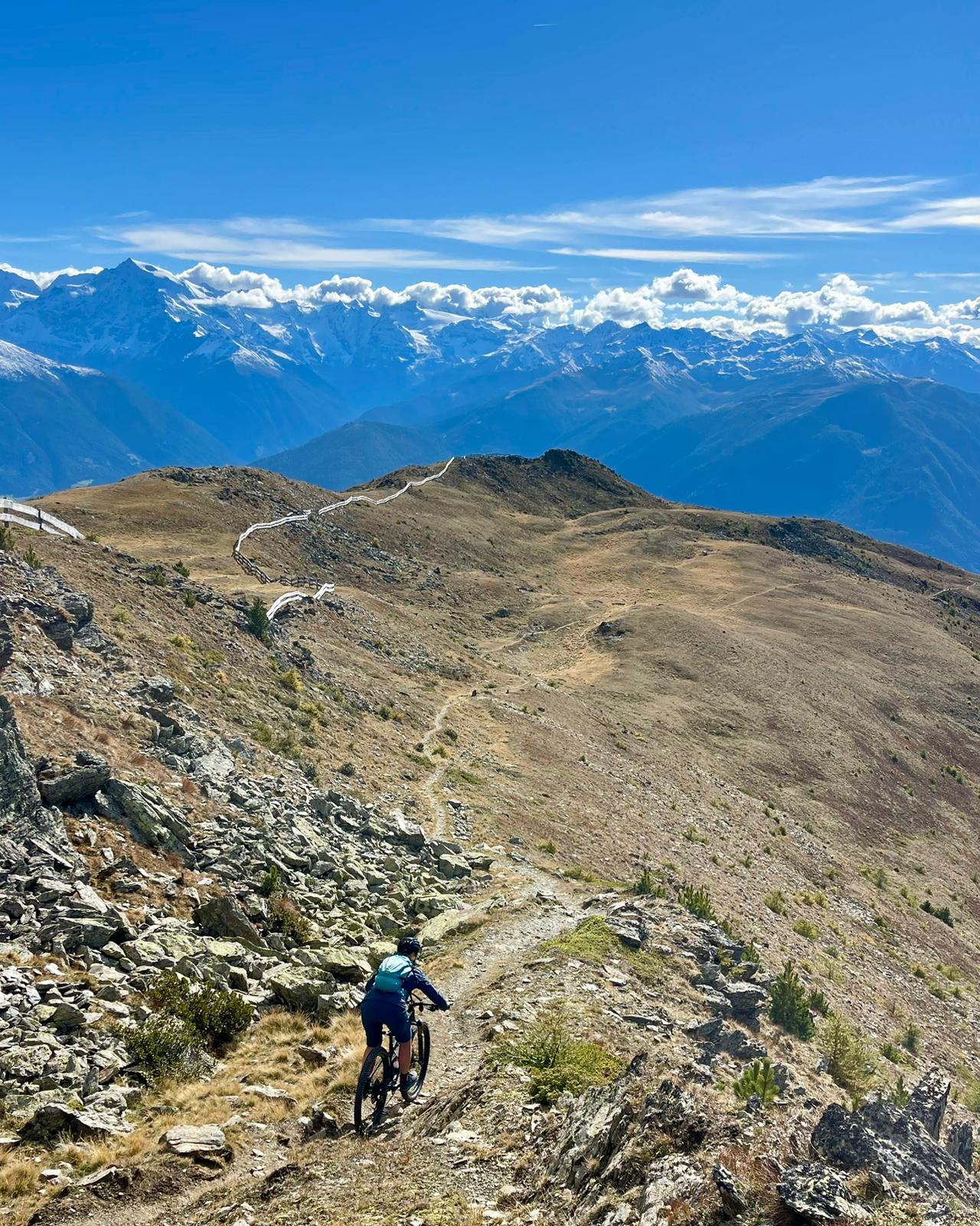 MTB-Fahrer auf steinigem Höhenweg mit Alpenpanorama
